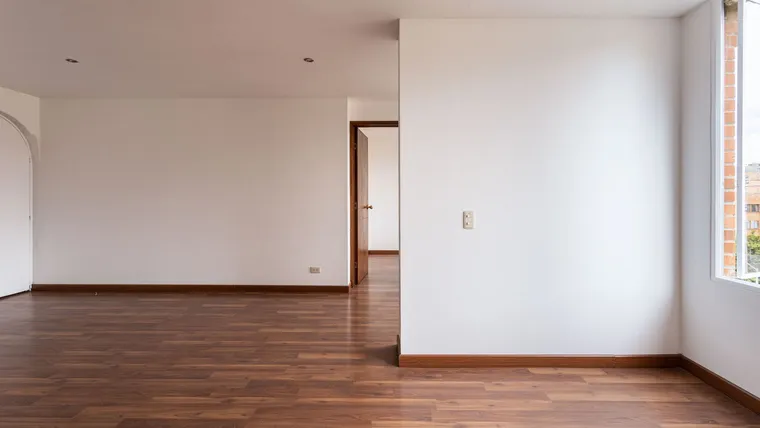 Red-brown laminate flooring in an empty room with white walls
