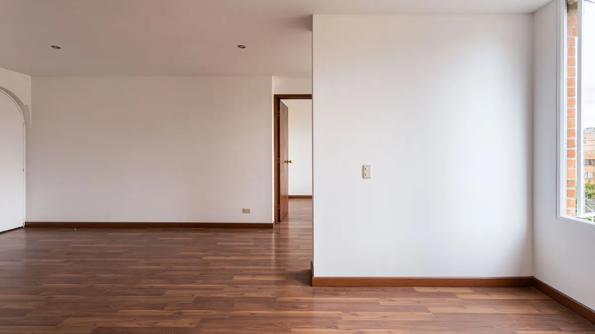 Red-brown laminate flooring in an empty room with white walls
