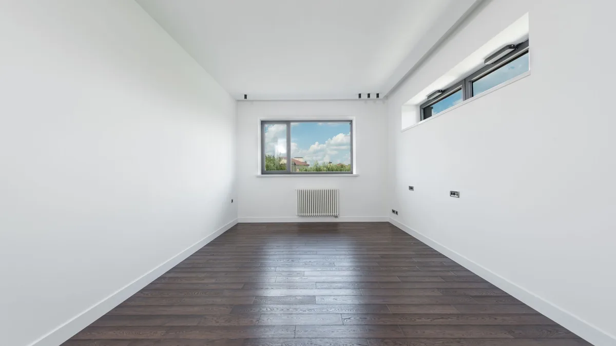 Dark brown laminate in a long, narrow room with white walls