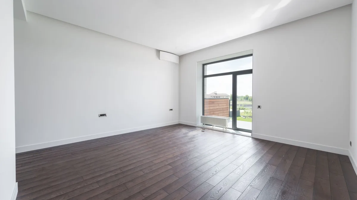 Dark laminate flooring in an empty room with a patio door