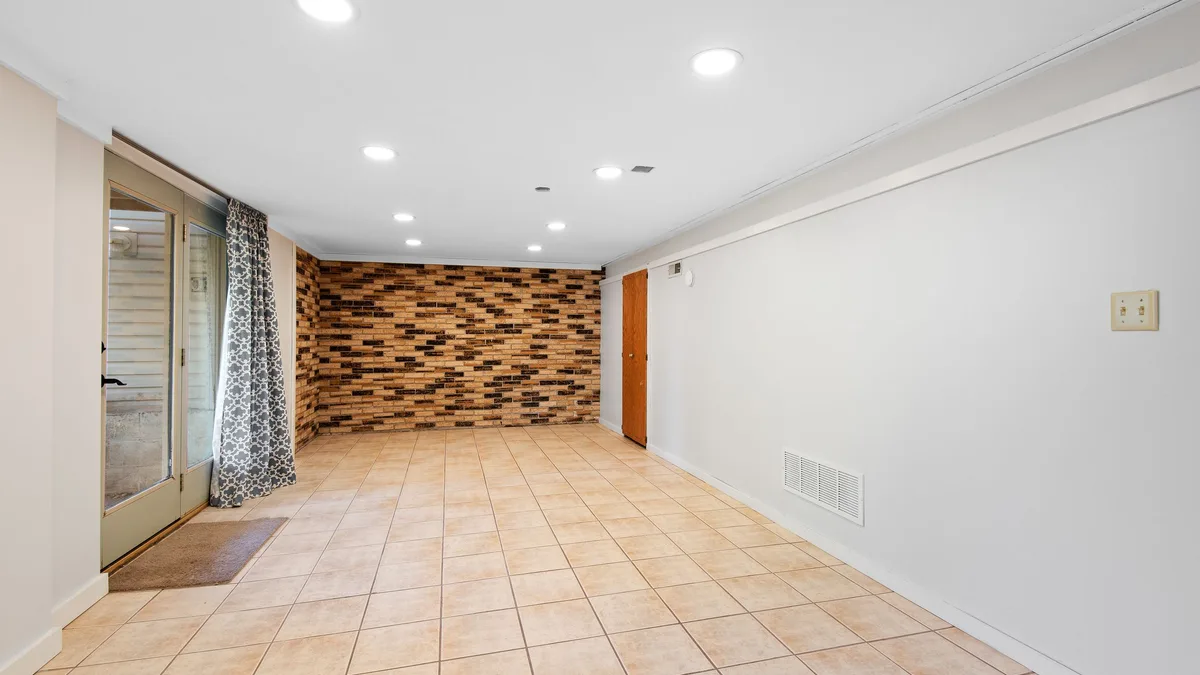 Cream floor tile in a basement room with a brick accent wall