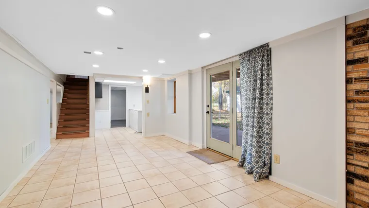 Cream floor tile in a walkout basement with glass doors and stairs