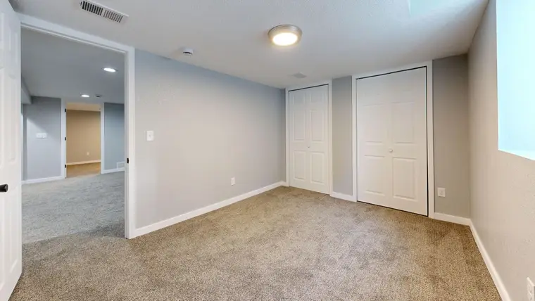 Beige carpet in a bedroom with closet doors, running through to the next room