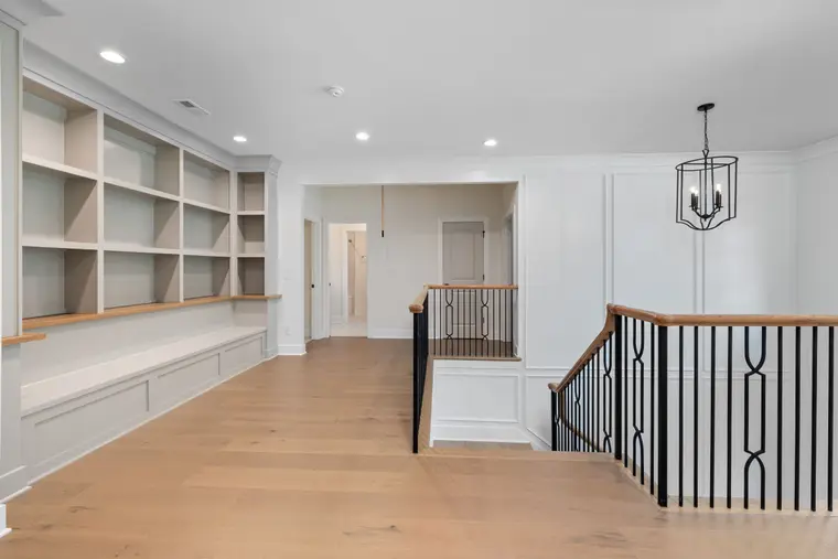 Wood-look flooring on a landing beside a stair railing and built-in shelves